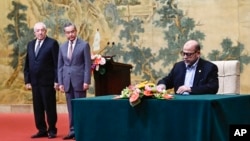 哈马斯高级成员穆萨·阿布·马尔祖克(Mussa Abu Marzuk,右)在北京钓鱼台国宾馆签署文件,中国外交部长王毅和法塔赫副主席马哈茂德·阿卢勒(Mahmoud al-Aloul)在一旁观看。(2024年7月23日)