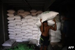 iLUSTRASI - Seorang buruh menurunkan karung beras dari kapal di sepanjang dermaga di Yangon, 28 Juni 2023. (Sai Aung MAIN / AFP)