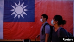 台北街头民众走过竖立的台湾旗帜。(2023年8月18日)