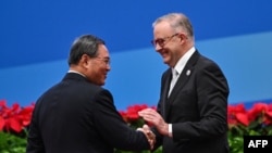 资料照:中国总理李强与澳大利亚总理阿尔巴尼斯在上海举办的第六届中国国际进口博览会开幕式上握手。(2023年11月5日)