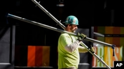 资料照片：2024年3月14日，波士顿一名建筑工人在搬运脚手架零件。(美联社照片)