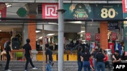 2023 年 4 月 14 日,在印度尼西亚主要岛屿爪哇岛以北的海域发生 7.0 级地震后,一家百货公司的员工在度假胜地巴厘岛登巴萨的大楼外等候。