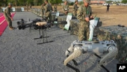 资料照:在柬埔寨金边北部举行的中柬“金龙”联合军演举行之前,中国军人(右)在检验机器狗。(2024年5月16日)