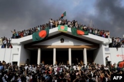 孟加拉国反政府示威者在占领位于首都达卡时总理官邸后展示孟加拉国国旗(2024年8月5日)