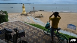 资料照:一名男子在中国厦门用一副望远镜隔海遥望台湾金门岛。(2022年8月3日)