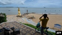 资料照:一名男子在中国福建厦门用一副望远镜隔海遥望台湾金门岛。(2022年8月3日)