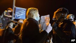 在北亚利桑那大学,一名支持巴勒斯坦人的抗议者举着标语与警察对峙。(2024年4月30日)