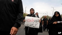 2024年8月25日，在纪念先知穆罕默德的孙子伊玛目·侯赛因在公元680年被杀后40天哀悼期结束的仪式上，一名哀悼者举着一块标语牌，上面写着：“加沙浸泡在儿童的鲜血中”。(美联社照片)