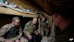 资料照片:一名随军神职人员在东正教复活节前夜在哈尔科夫州前线附近的掩体内与乌军士兵交谈。(2023年4月15日)