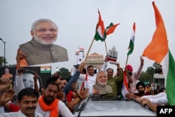 印度民众在新德里挥舞国旗和总理莫迪画像庆祝印度“月船3号”太空探测器星期三(8月23日)成功在月球南极表面软着陆。