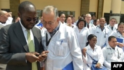 资料照片:肯尼亚基苏木省省长安扬·尼永戈教授(左)与参加位于内罗毕肯尼亚政府学院项目的100名古巴医生之一交谈。(2018年6月11日)