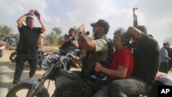 2023年10月7日,一名被俘的以色列平民(中,穿红衣的女士)被从卡法阿扎基布兹运送到加沙地带。(AP Photo/Hatem Ali)