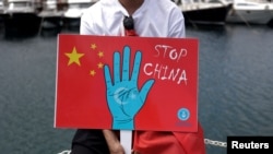 Seorang demonstran Uighur membawa poster yang bersisi seruan untuk menghentikan China dalam aksi protes di Istanbul, Turki, pada 5 Juli 2023. Aksi itu digelar untuk menandai peringatan 14 tahun kerusuhan Urumqi. (Foto: Reuters/Murad Sezer)