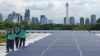 Para pekerja berjalan di dekat rangkaian panel surya penyedia sebagian energi listrik bagi Masjid Istiqlal, Jakarta. Renovasi besar-besaran pada tahun 2019 mencakup pemasangan 500 panel surya di atap masjid itu kini menjadi sumber energi bersih Istiqlal.