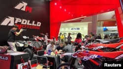 2023年4月15日在广州举行的“广交会”上,参观者在询问Apollo Motors展出的摩托车等产品。