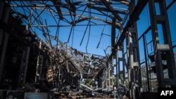 在敖德萨,当地人查看被一枚俄罗斯导弹击中的工业建筑残骸。(2023年5月18日)