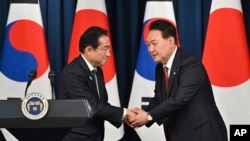 2023年5月7日,韩国总统尹锡悦和日本首相岸田文雄在首尔韩国总统办公楼举行双方会谈后召开的联合记者会上相互握手致意。