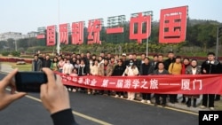 中国福建厦门竖立起一个台湾金门岛可以看到的“一国两制统一中国”的大型标语牌,旅游者在前拍照。(2024年1月12日)