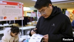 23岁的张百川(音译)在中国河北省石家庄市的招聘会上查看招工广告。(2024年2月24日)