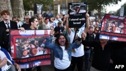 民众手举被巴勒斯坦武装分子劫为人质的以色列妇女和儿童的照片在伦敦的英国首相官邸唐宁街10号外举行集会。(2023年10月9日)