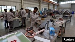 资料照:印度艾哈迈达巴德市郊的一座工厂内工人正在组装变压器。(2024年3月28日)