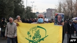 2024年1月12日，在德黑兰举行的支持也门和巴勒斯坦人的抗议活动中，一名抗议者举着阿富汗什叶派组织的旗帜，该组织成立于 2014 年，在叙利亚与该政权并肩作战。（法新社照片）