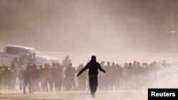 2023年4月25日,从墨西哥华雷斯城看到的移民在越过布拉沃河后,站在边境墙附近,打算向美国边境巡逻队特工自首。(路透社照片)