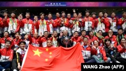 Para pemain bulu tangkis putra China berpose dengan trofi setelah mengalahkan Indonesia dalam final turnamen bulu tangkis Piala Thomas dan Uber di Chengdu, 5 Mei 2024. (Foto: WANG Zhao/AFP)
