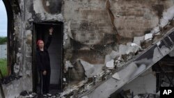 在乌克兰奥里希夫,一位当地女子站在被俄军袭击摧毁的基督教福音派浸信会的祈祷堂的废墟下。(2022年5月22日)
