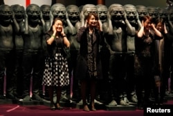 香港苏富比拍卖中国艺术家岳敏君的作品前观众与他的作品合影。（2011年3月31日）