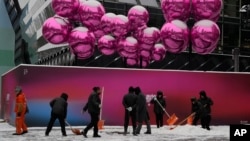 北京一家已经为圣诞节装饰起来的商场外工人们在清除积雪。（2023年12月14日）