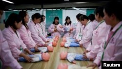 上海Yipeitong培训中心用塑料娃娃培训妇女成为有照顾新生儿技能的月嫂。(2023年3月2日)