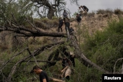 一组来自中国的移民渡过美墨边境的格兰德河走出美国德克萨斯州的丛林,他们寻找美国执法人员以便进入移民程序。(2023年4月4日)