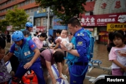 由志愿者组成的中国民间救援队蓝天救援队成员在河南郑州对洪灾灾民实行救援。(2021年7月22日)