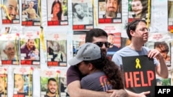 在2023年10月7日遭哈马斯武装分子劫持的人质照片前,至今被扣押的人质家属与支持者在特拉维夫以色列国防部外举行抗议活动,呼吁政府采取行动释放人质。(2024年4月25日)