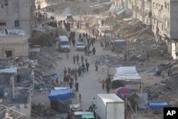 Warga Palestina berjalan di antara puing-puing setelah serangan udara dan darat Israel di Khan Younis, Jalur Gaza selatan, Rabu, 15 Mei 2024. (Foto: AP/Saher Alghorra)