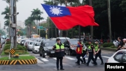 台湾警察护送一名举着台湾旗帜的男子走过台北街头。(2024年5月24日)