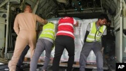 在沙特一个机场一队利雅得救援人员将运往苏丹的救援物质推进一架军用运输机的机舱内。(2023年5月10日)