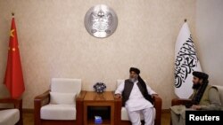 2023年10月19日,塔利班代理商务部长阿齐齐在阿富汗驻中国北京大使馆接受路透社采访时坐在阿富汗伊斯兰酋长国和中国国旗中间。(路透社照片)