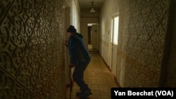 一位在康斯坦丁尼夫卡的庇护所栖身的前巴赫穆特居民试图打开她暂时为家的房门。(2023年4月11日,美国之音博夏特拍摄)