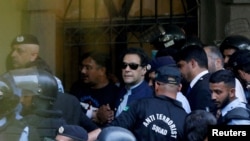 资料照片:2023年5月12日,安全人员在巴基斯坦伊斯兰堡护送前总理伊姆兰·汗(中)在伊斯兰堡高等法院出庭。(路透社照片)