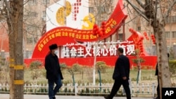 资料照：新疆和田居民走过街头竖立的社会主义核心价值观的宣传牌。（2021年3月22日）