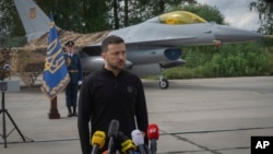 资料照片:乌克兰总统泽连斯基在站在一家乌克兰空军F-16战斗机前回答记者的提问。(2024年8月4日)