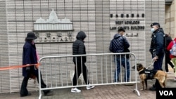 军装警员牵着警犬监察进入西九龙裁判法院大楼，旁听香港壹传媒创办人黎智英国安案的市民 (美国之音/汤惠芸)