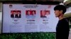 Seorang pria berjalan melewati spanduk Komisi Pemilihan Umum yang menampilkan foto-foto kandidat presiden di Jakarta, Senin, 22 Januari 2024. (Foto: AP)