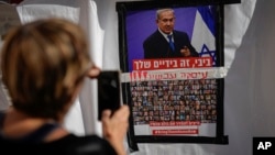 以色列特拉维夫的一名女子用手机拍摄的一张海报照片显示,内塔尼亚胡总理照片下贴有被关押在加沙的以色列人质的照片,海报要求以色列领导人达成协议将人质带回家。(2023年11月21日)