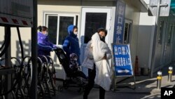 FILE - Seorang perempuan menggendong seorang anak saat mereka meninggalkan rumah sakit anak-anak di Beijing, Jumat, 24 November 2023. (AP/Ng Han Guan)