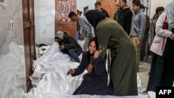 2024年3月5 日,在加沙地带南部汗尤尼斯的欧洲医院太平间,巴勒斯坦人在以色列轰炸中丧生的亲属尸体旁边哀悼。(法新社照片)