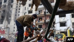 俄罗斯导弹袭击摧毁基辅中心的高楼后,工作人员修复楼外水管。(2024年1月3日)