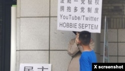 2023年6月22日,网传北京大学一食堂门外有年轻人举牌呼唤民主革命和多党制取代一党极权。(推特图片)